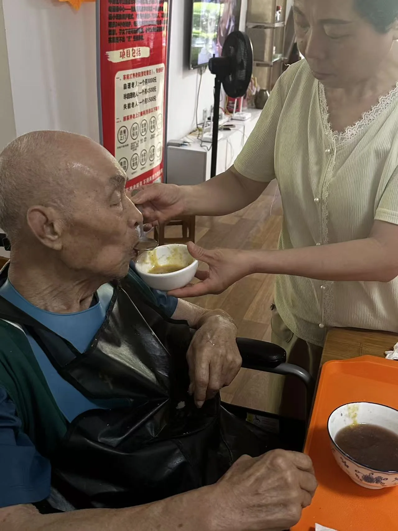 护理员喂食坐轮椅老人